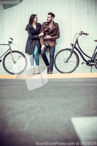 Image of Young couple with a bicycle opposite city 