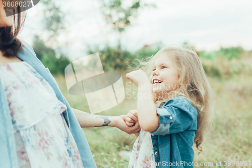 Image of The young mother and daughter on green grass background 