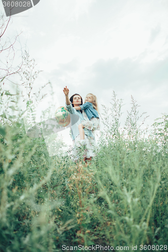 Image of The young mother and daughter on green grass background 
