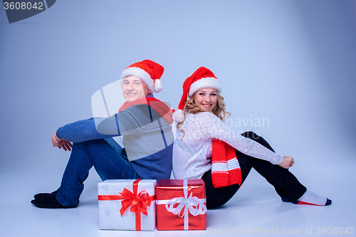 Image of Lovely christmas couple sitting with presents