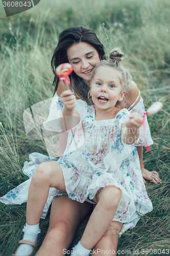 Image of The young mother and daughter on green grass background 