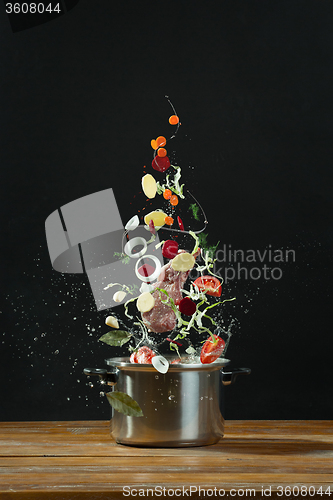 Image of Fresh vegetables falling into a stainless steel casserole 