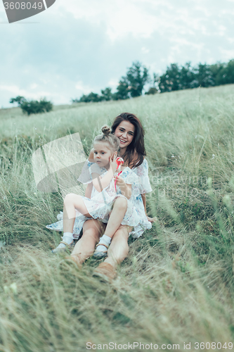 Image of The young mother and daughter on green grass background 