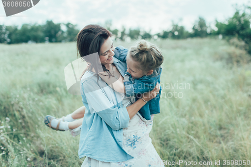 Image of The young mother and daughter on green grass background 