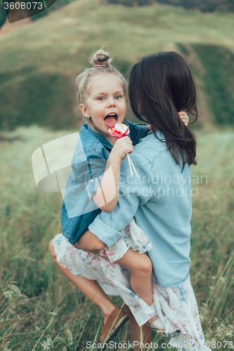 Image of The young mother and daughter on green grass background 