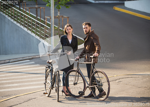 Image of Young couple with on a bicycle opposite city 