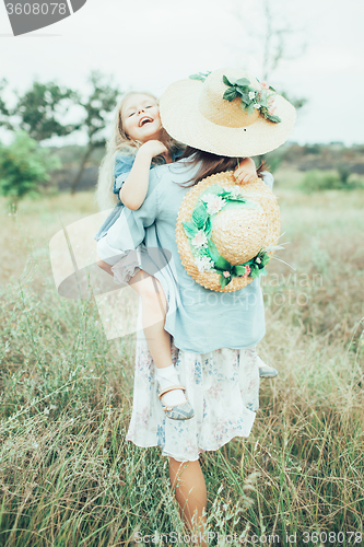 Image of The young mother and daughter on green grass background 