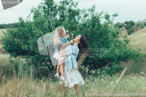 Image of The young mother and daughter on green grass background 