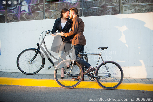 Image of Young couple with a bicycle opposite city 