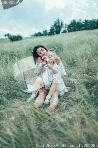 Image of The young mother and daughter on green grass background 
