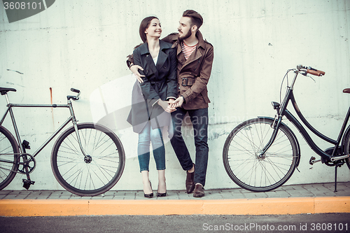 Image of Young couple with a bicycle opposite city 