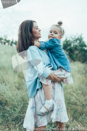 Image of The young mother and daughter on green grass background 