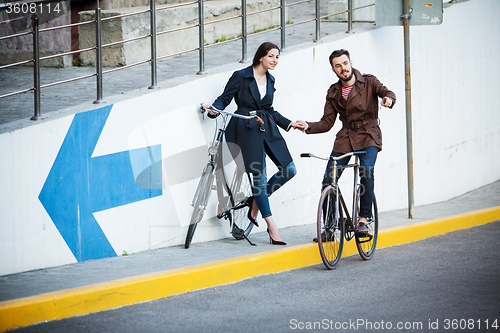 Image of Young couple with a bicycle opposite city 