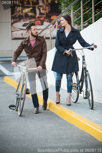 Image of Young couple with a bicycle opposite city 