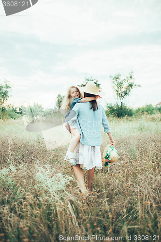 Image of The young mother and daughter on green grass background 