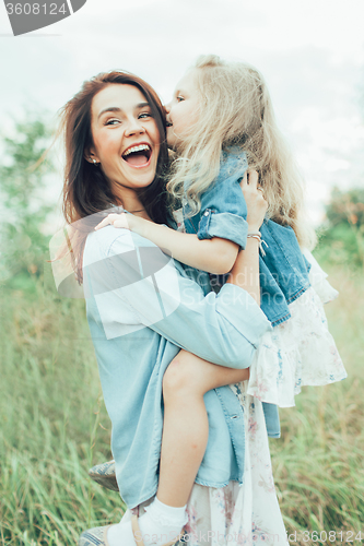 Image of The young mother and daughter on green grass background 