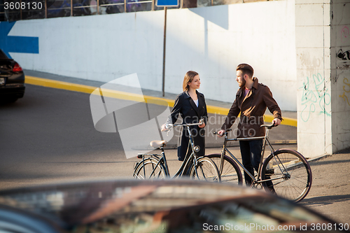 Image of Young couple with a bicycle opposite city 