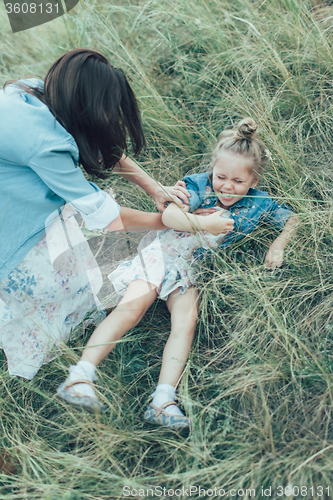 Image of The young mother and daughter on green grass background 