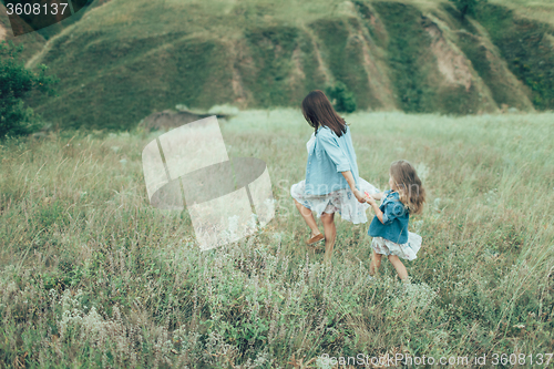 Image of The young mother and daughter on green grass background 