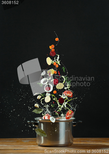 Image of Fresh vegetables falling into a stainless steel casserole 