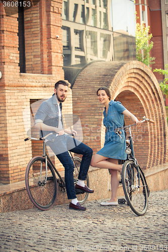 Image of Young couple sitting on a bicycle opposite city 