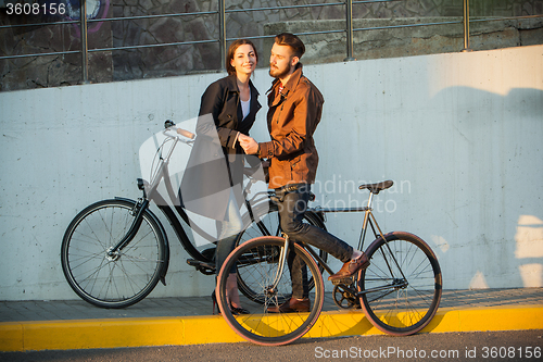 Image of Young couple with a bicycle opposite city 