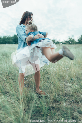 Image of The young mother and daughter on green grass background 
