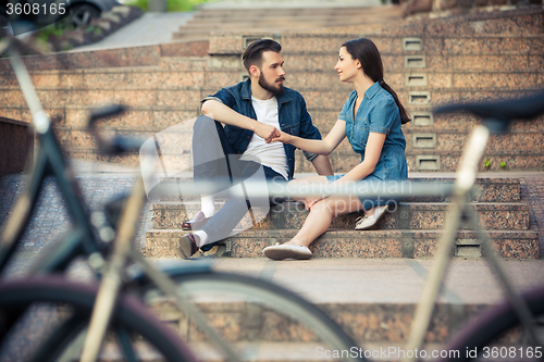 Image of Young couple sitting opposite  a bicycle 