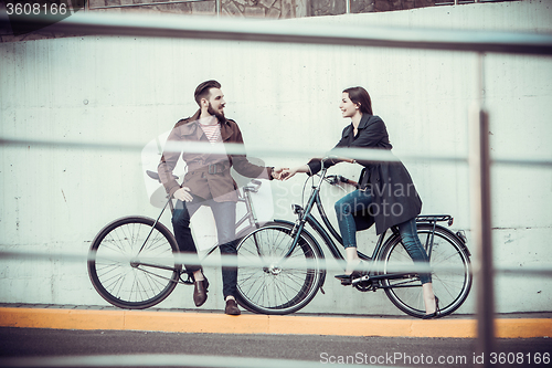 Image of Young couple with a bicycle opposite city 