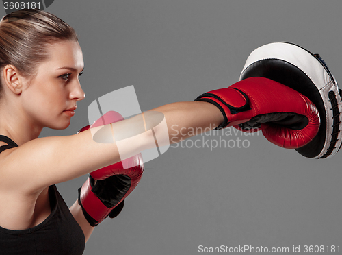 Image of beautiful woman is boxing on gray background
