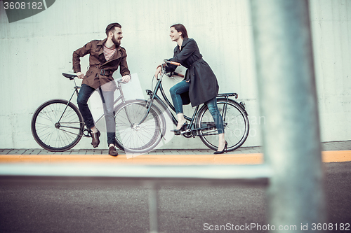 Image of Young couple with a bicycle opposite city 