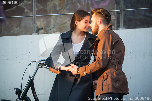 Image of Young couple with a bicycle opposite city 