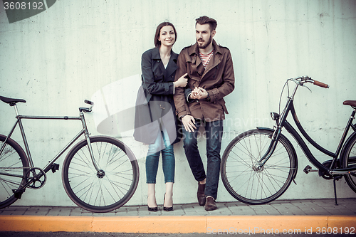 Image of Young couple with a bicycle opposite city 