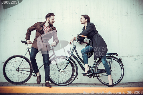 Image of Young couple with a bicycle opposite city 