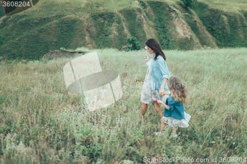 Image of The young mother and daughter on green grass background 