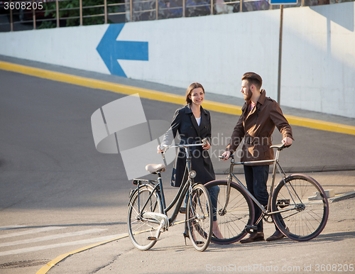 Image of Young couple with on a bicycle opposite city 