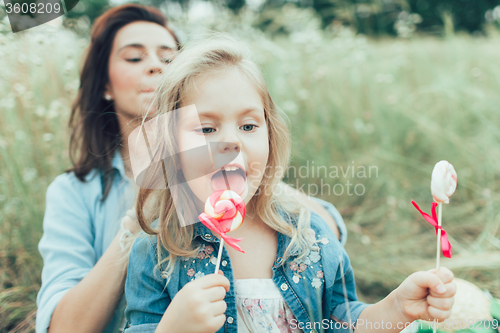 Image of The young mother and daughter on green grass background 