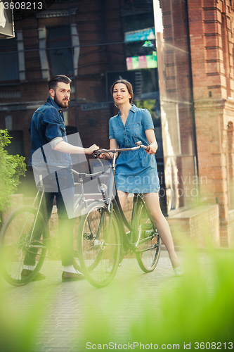 Image of Young couple sitting on a bicycle opposite the city 