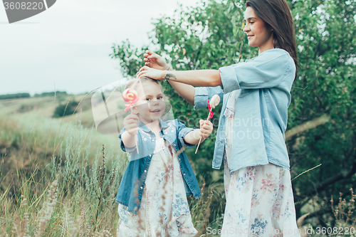 Image of The young mother and daughter on green grass background 