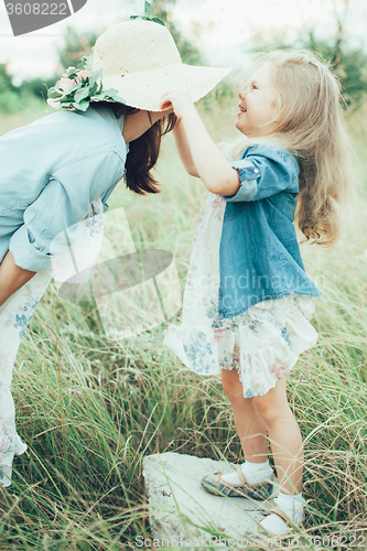 Image of The young mother and daughter on green grass background 