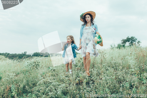 Image of The young mother and daughter on green grass background 