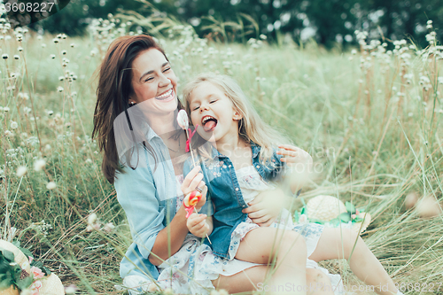 Image of The young mother and daughter on green grass background 