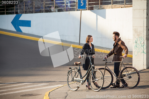 Image of Young couple with a bicycle opposite city 