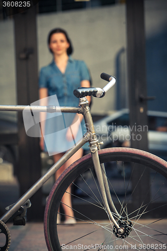 Image of Young girl with a bicycle opposite city 