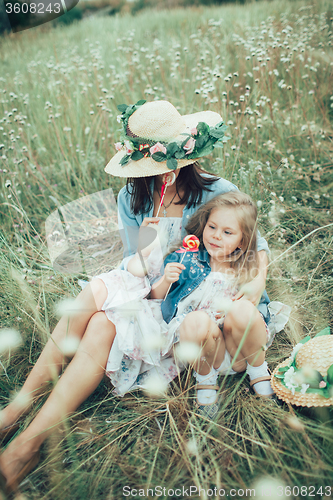 Image of The young mother and daughter on green grass background 