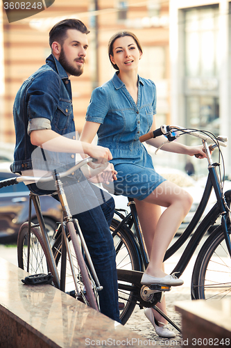 Image of Young couple sitting on a bicycle opposite city 