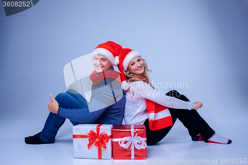 Image of Lovely christmas couple sitting with presents