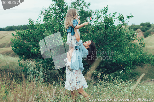 Image of The young mother and daughter on green grass background 