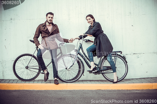 Image of Young couple with a bicycle opposite city 