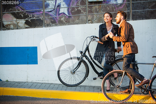 Image of Young couple with a bicycle opposite city 